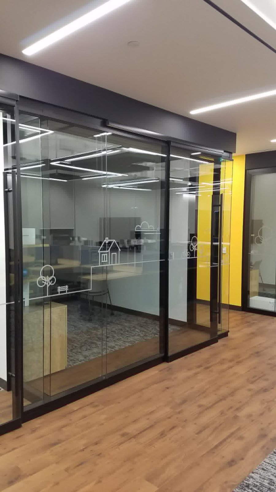 Glass meeting room with sliding doors and yellow accent wall